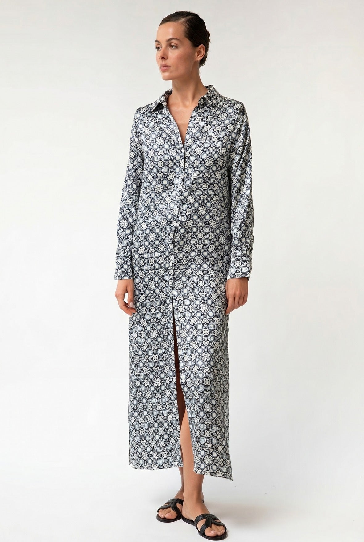 Woman wearing a long, black and white silk-patterned dress against a white background. Nokaya