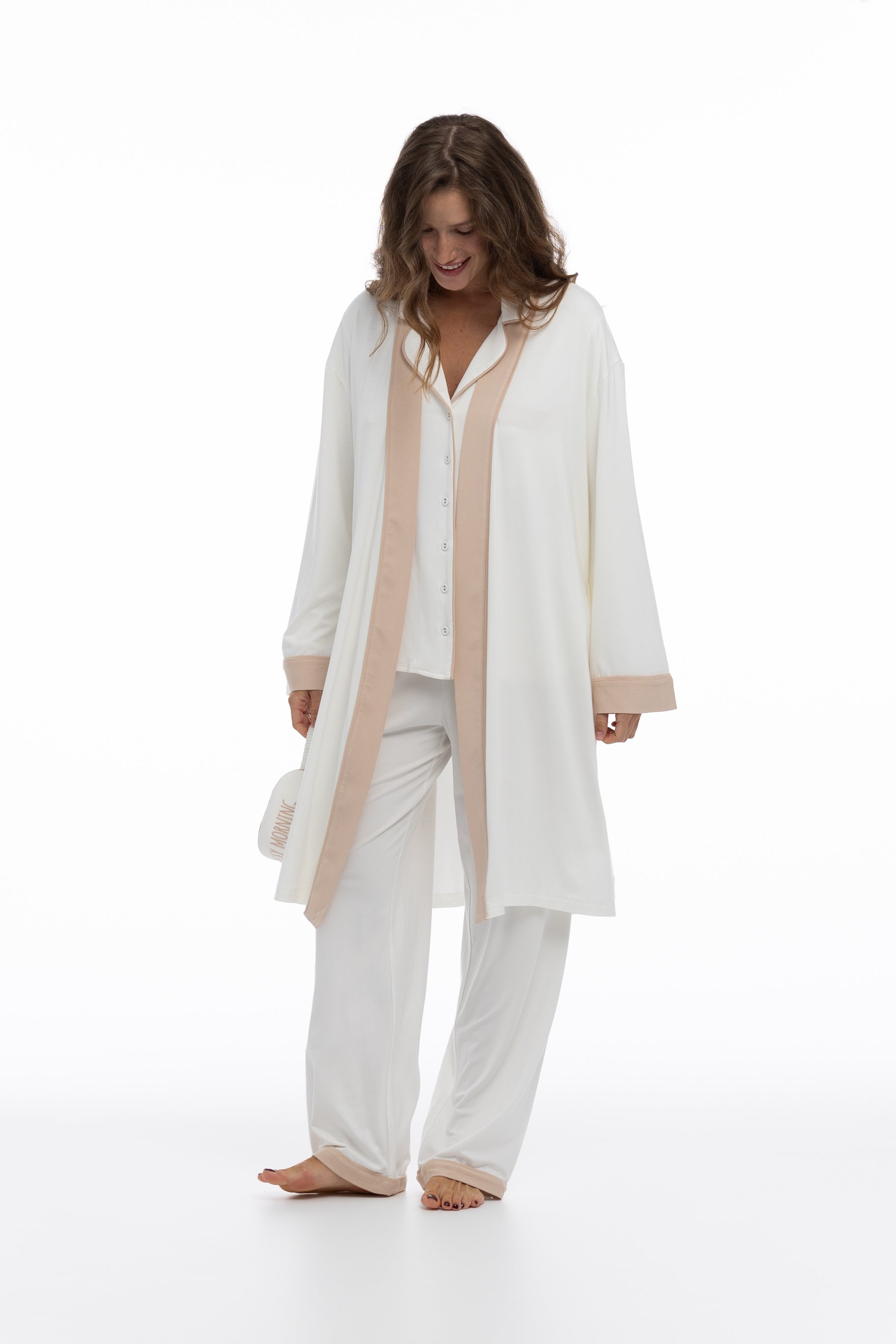Woman wearing bamboo white pyjamas and robe Nokaya with beige accents on a white background