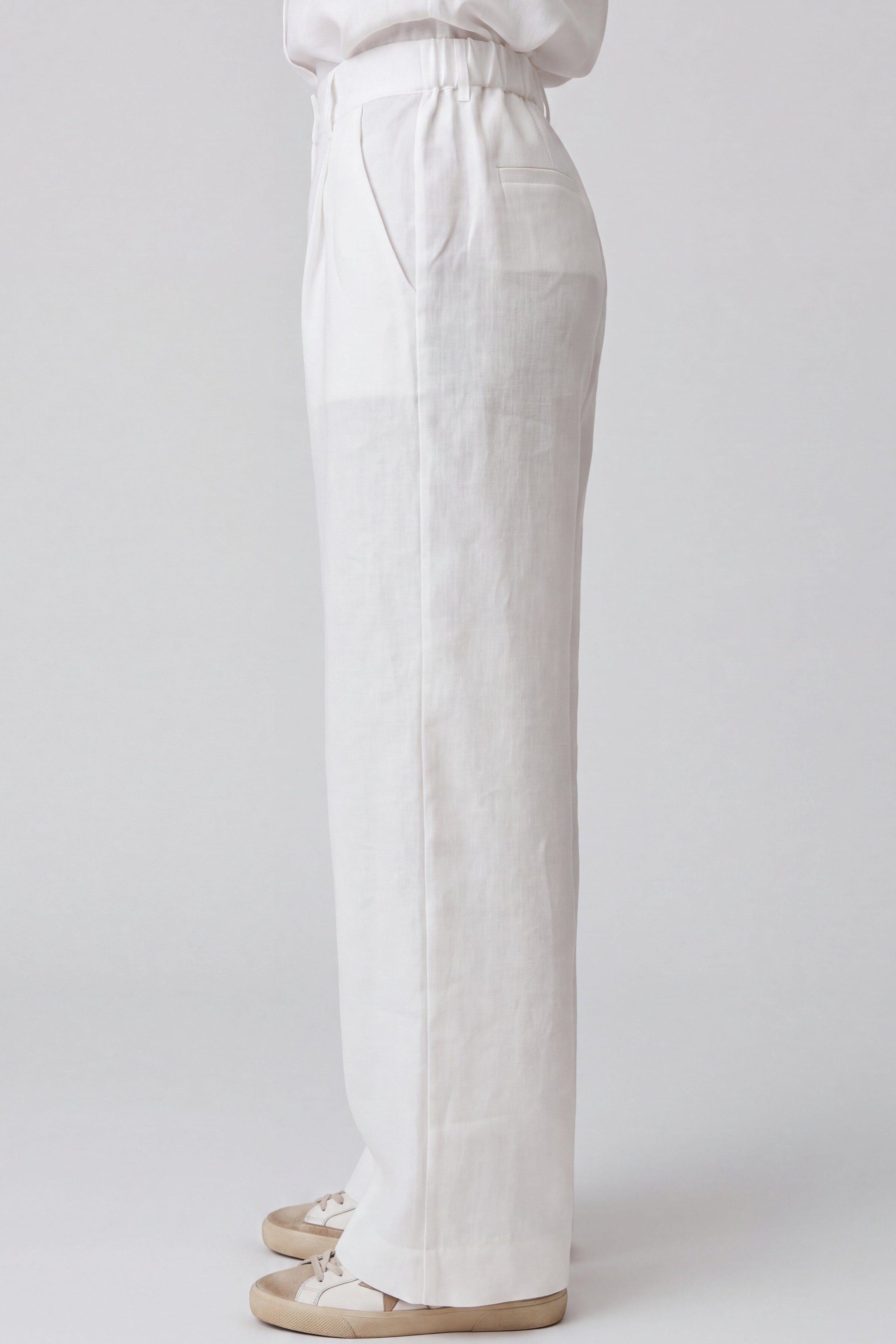 Linen trousers Nokaya on the grey background. Side View. Elastic belt at the back