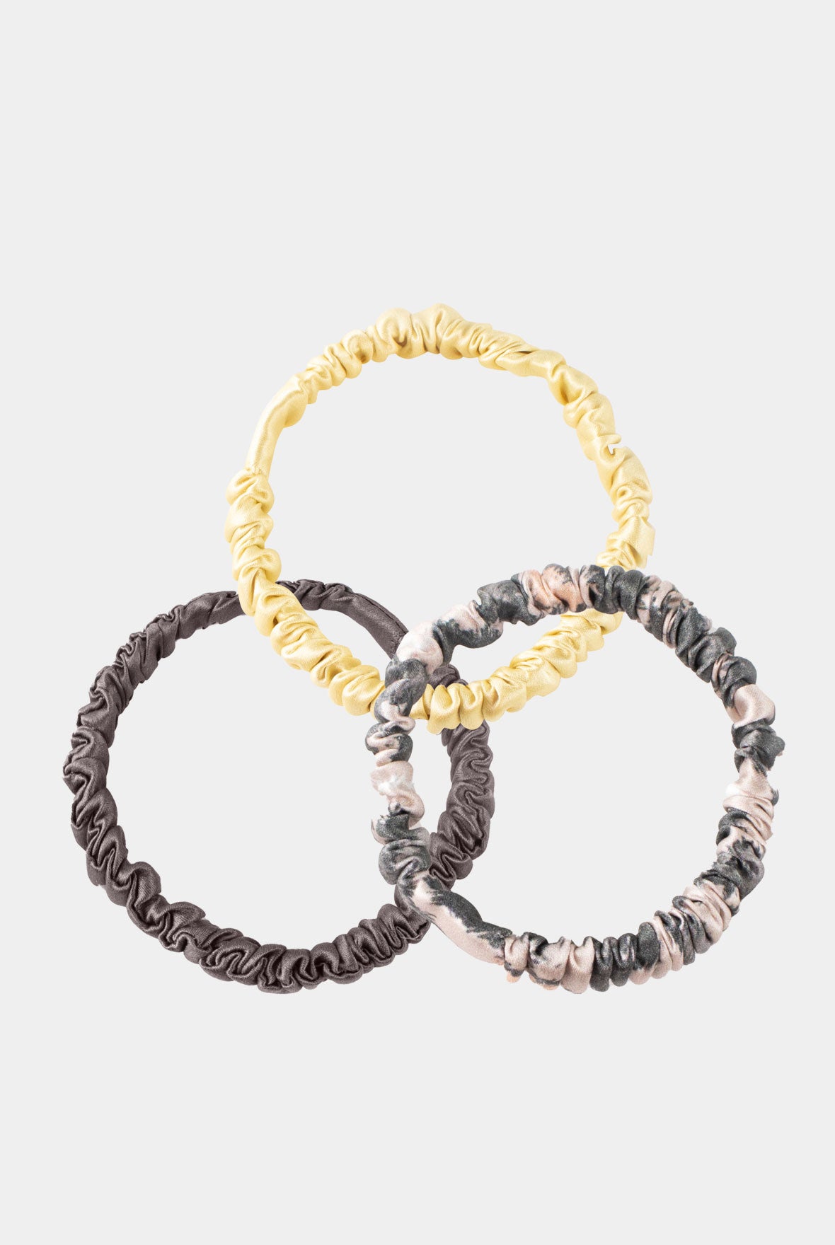 Three hair scrunchies in gold, brown, and animal print on a light grey background, Nokaya.