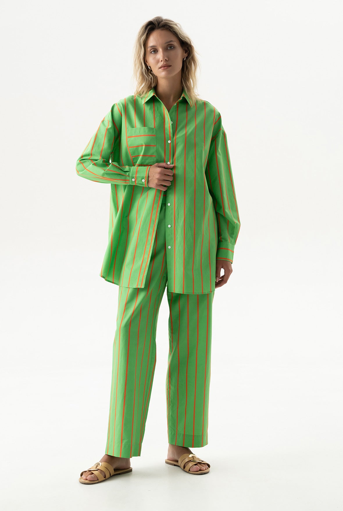 Woman wearing a green and red striped shirt and pants on a white background