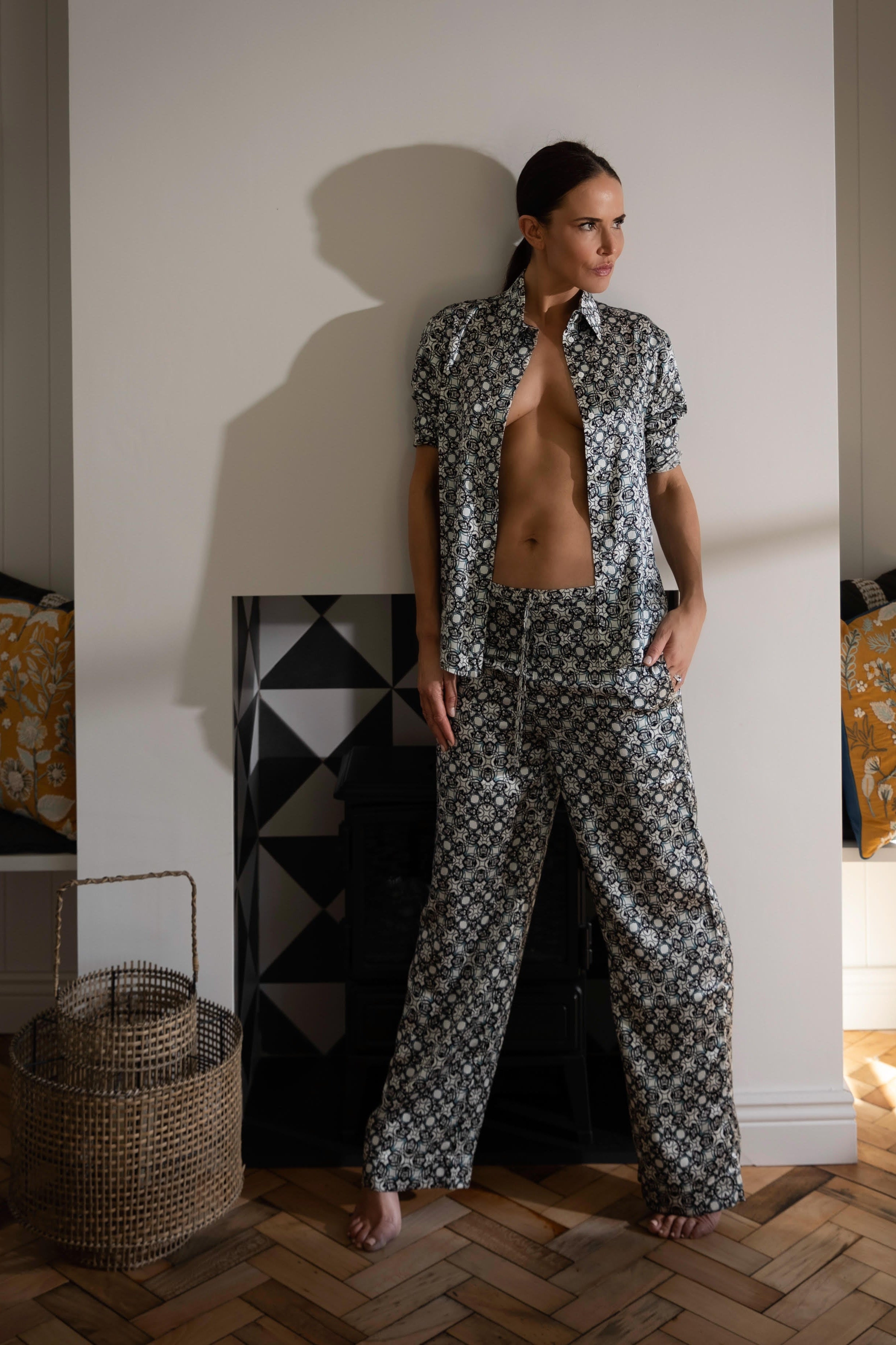 Silk Pyjama Pants in Black Crystal Neo Geo print - styled on a model near a fireplace, showcasing the relaxed fit and luxurious silk fabric for cosy homewear.
