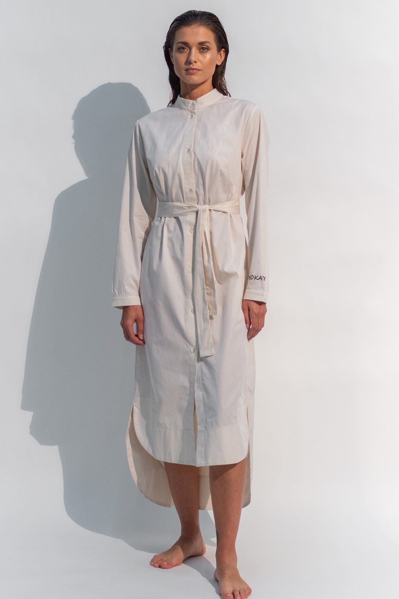 The Inner Matters cotton dress features a stylish, asymmetrical cut with a thin belt accentuating a silhouette.