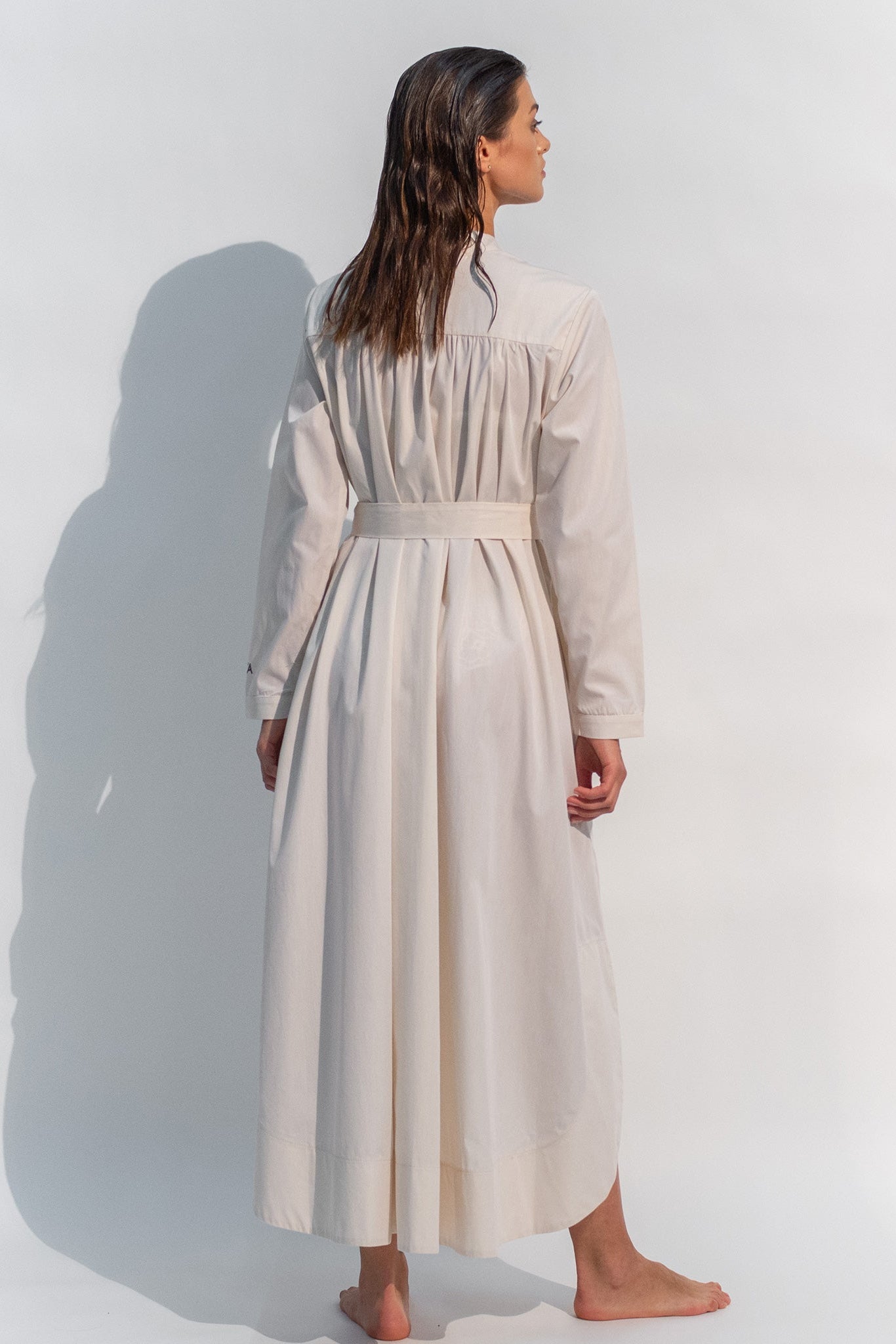 The Inner Matters cotton dress features a stylish, asymmetrical cut with a thin belt accentuating a silhouette.