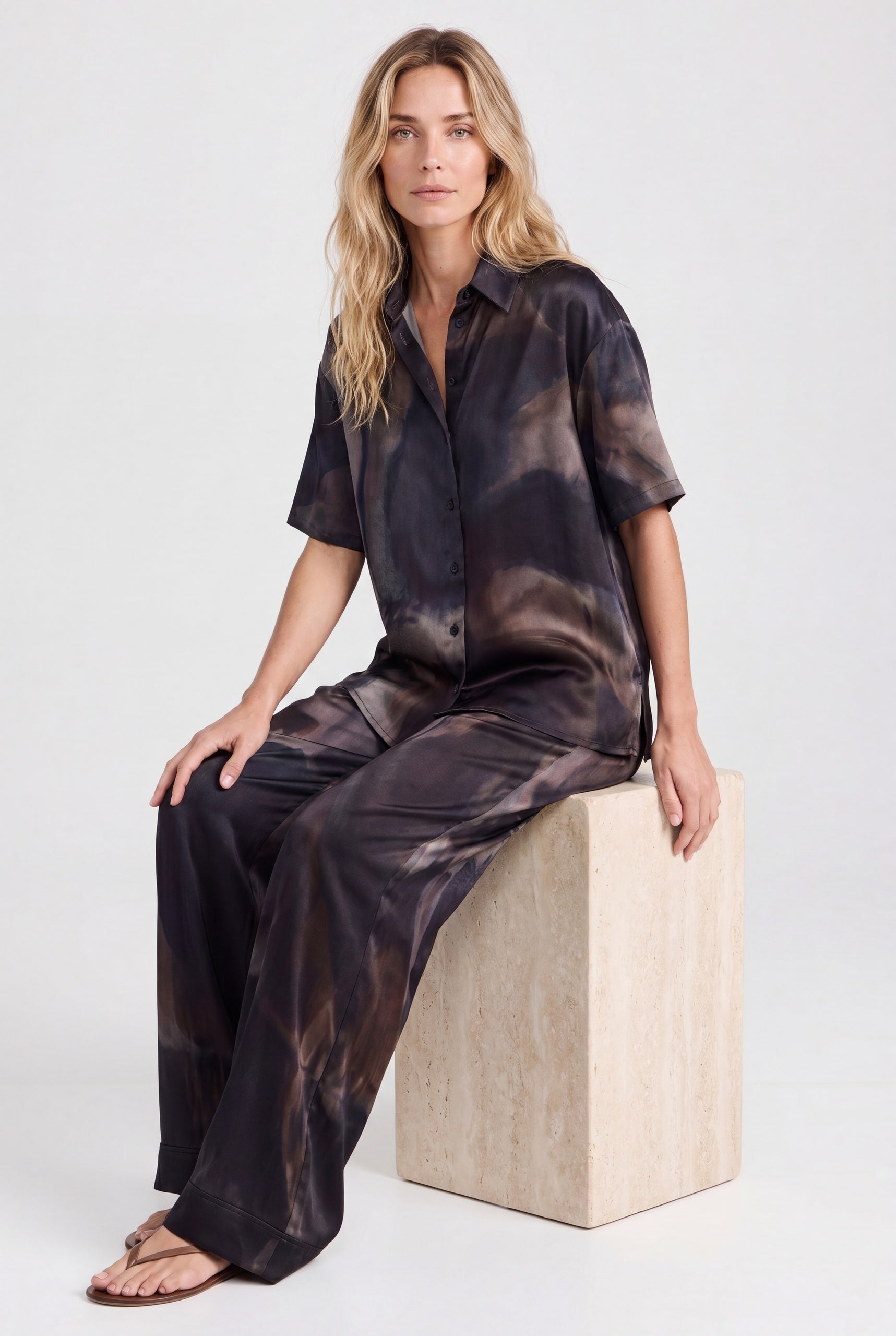 NOKAYA Mirage silk co-ord, seated on travertine plinth