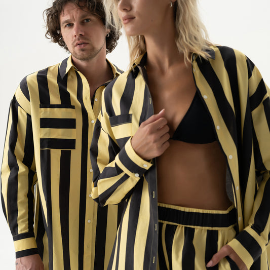 Two people wearing matching black and yellow striped outfits on a plain background Nokaya