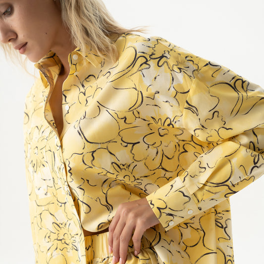Woman wearing a yellow floral dress against a white background Nokaya