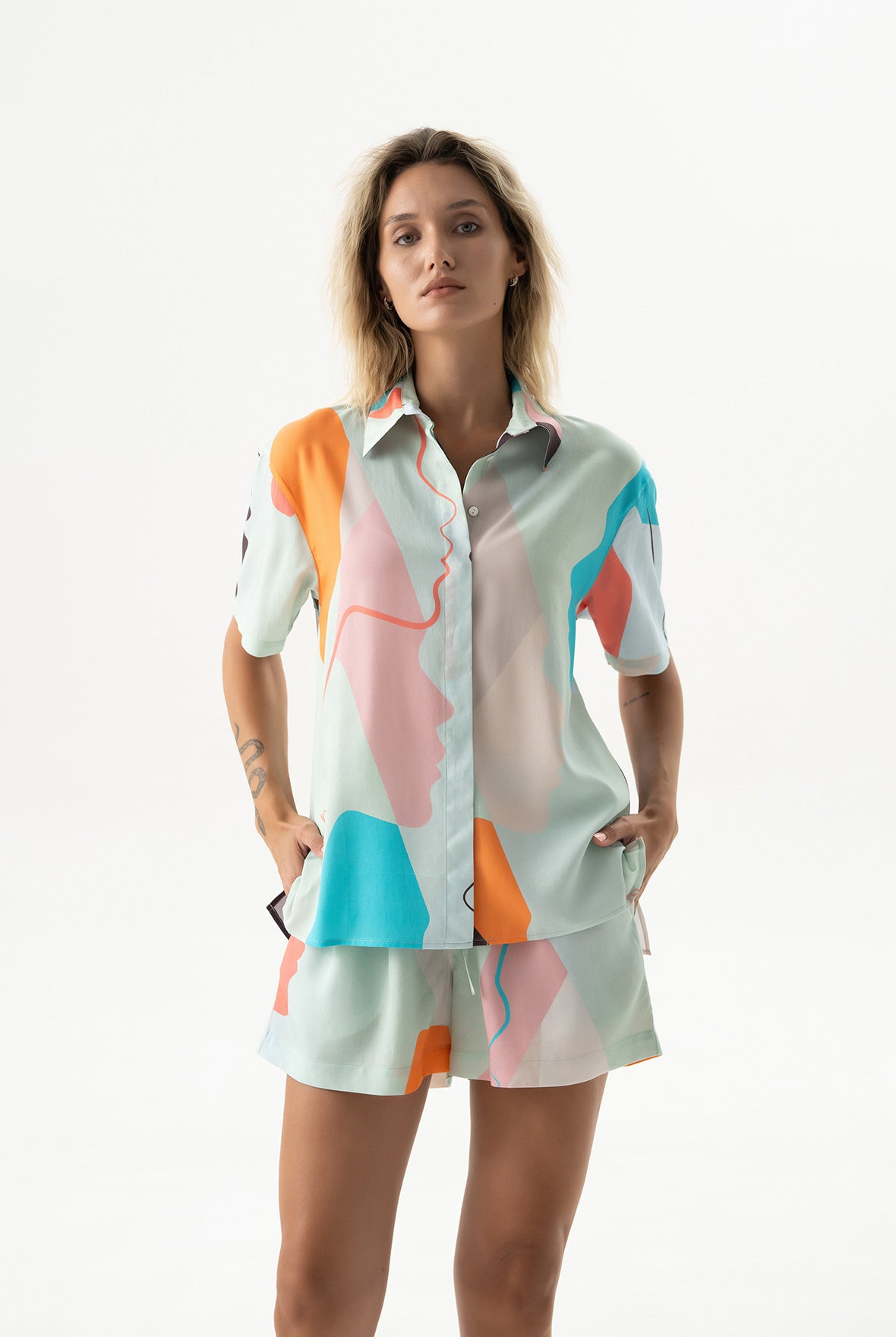 Woman wearing a colourful shirt, Nokaya, made of tencel, with abstract patterns on a white background