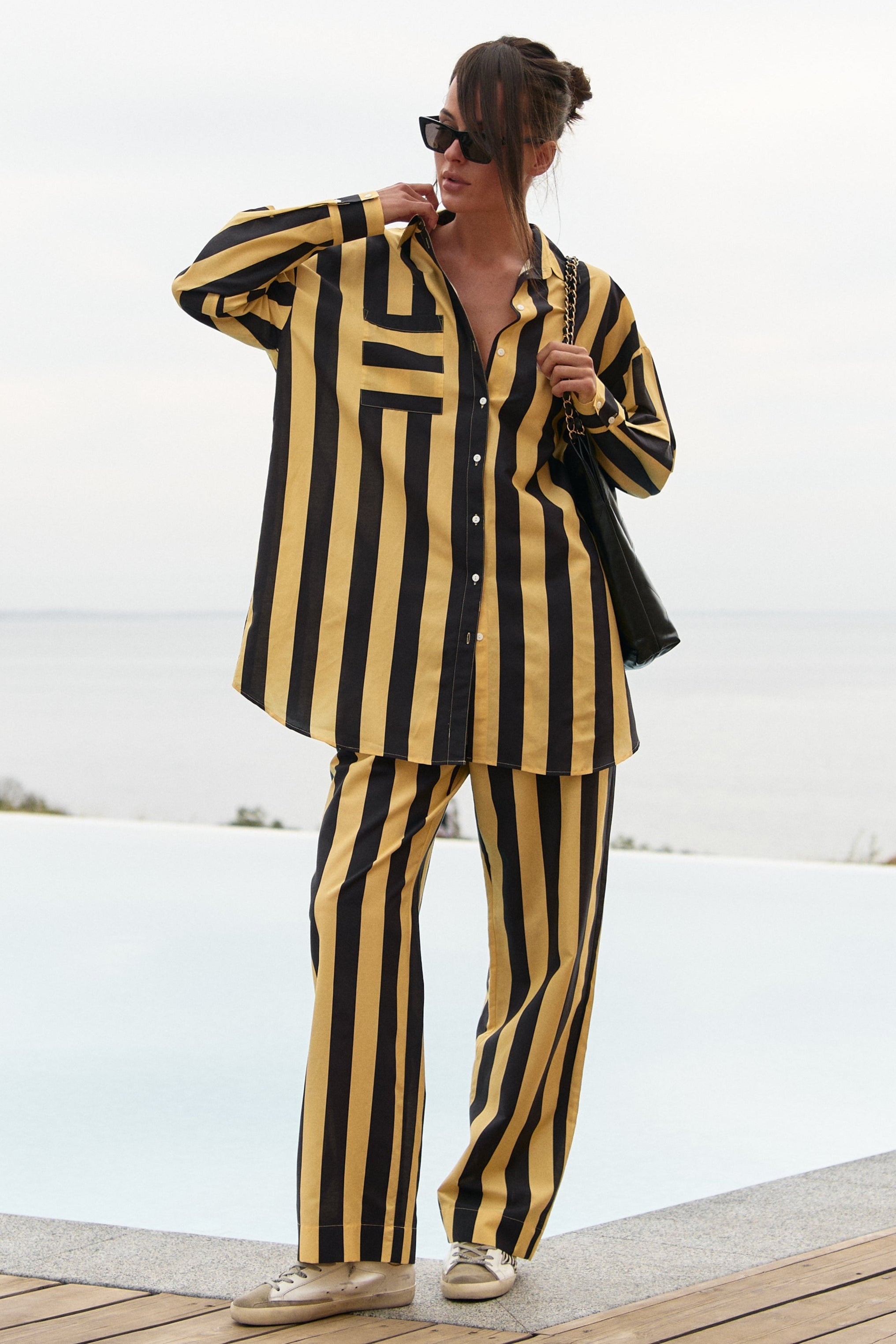 A person wearing a black and yellow striped Nokaya's outfit by a poolside.