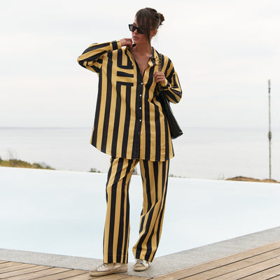 A person wearing a black and yellow striped Nokaya's outfit by a poolside.