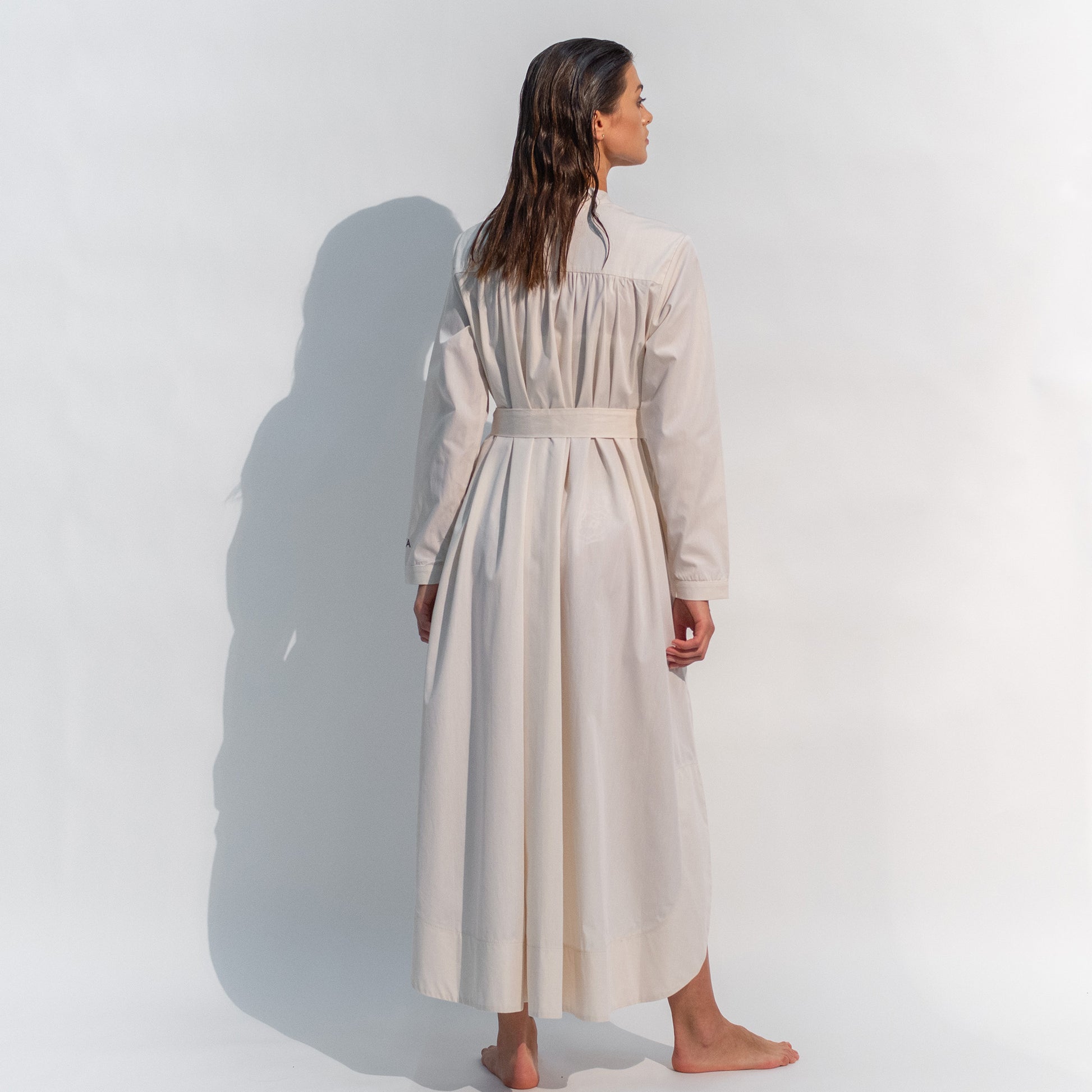 The Inner Matters cotton dress features a stylish, asymmetrical cut with a thin belt accentuating a silhouette.