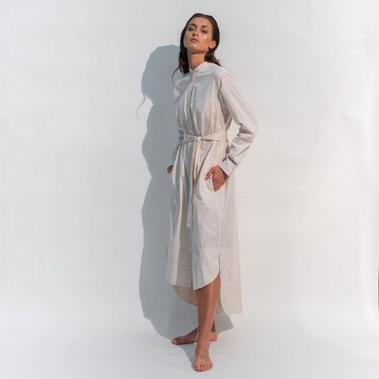 The Inner Matters cotton dress features a stylish, asymmetrical cut with a thin belt accentuating a silhouette.